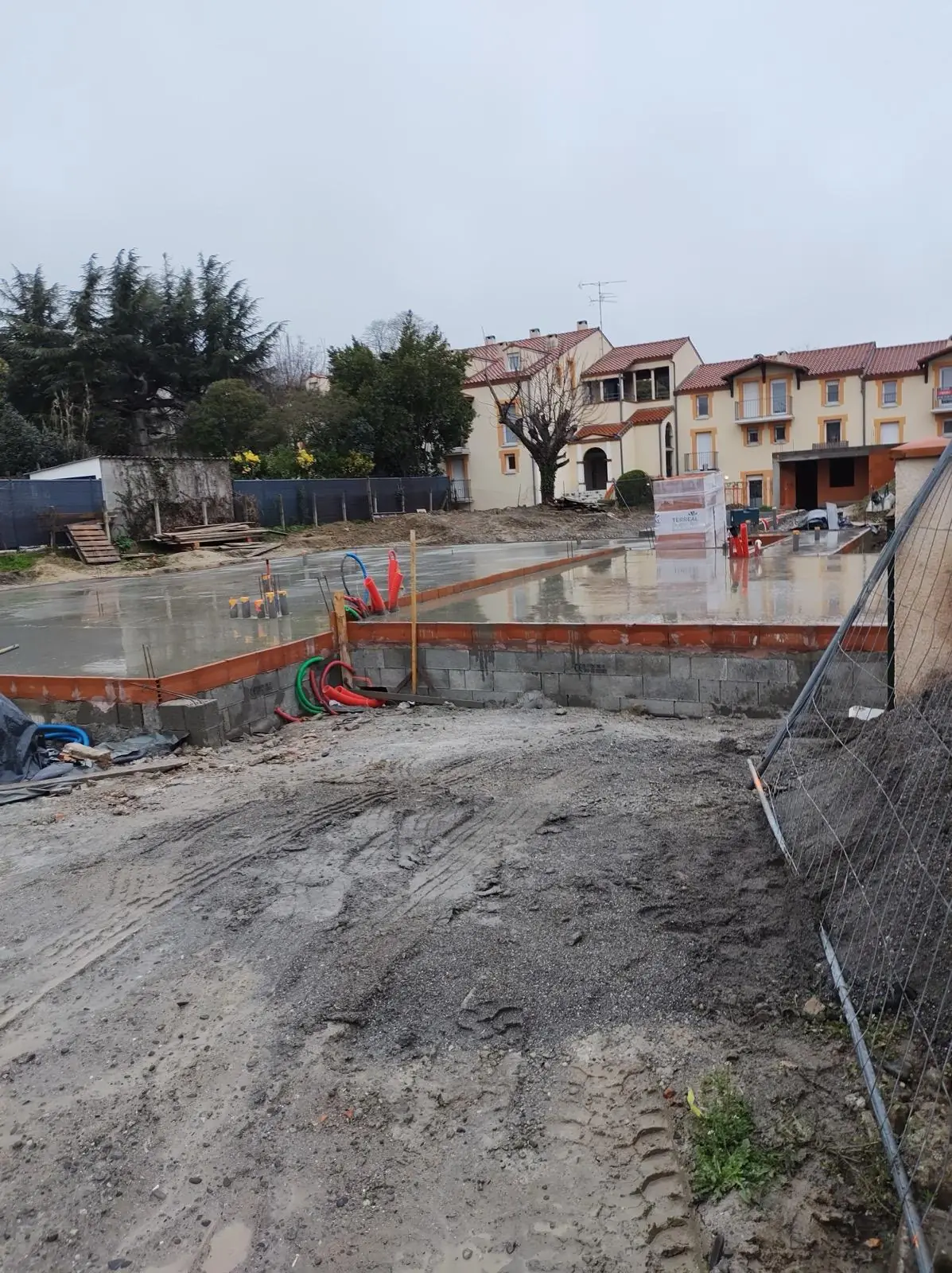 Dalle béton fraîchement coulée dans un quartier résidentiel, clôture de chantier