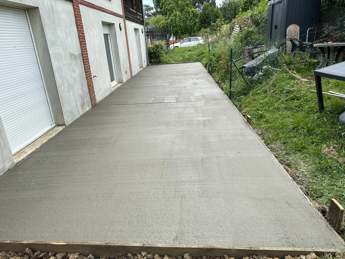 Allée en béton le long d'un garage, finition talochée