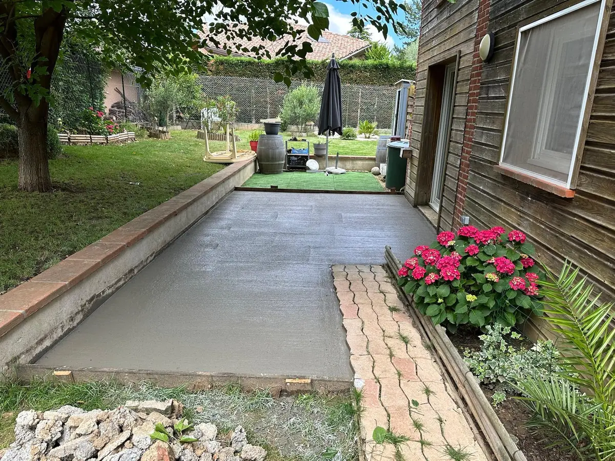 Terrasse béton dans un jardin aménagé, bordure en briques