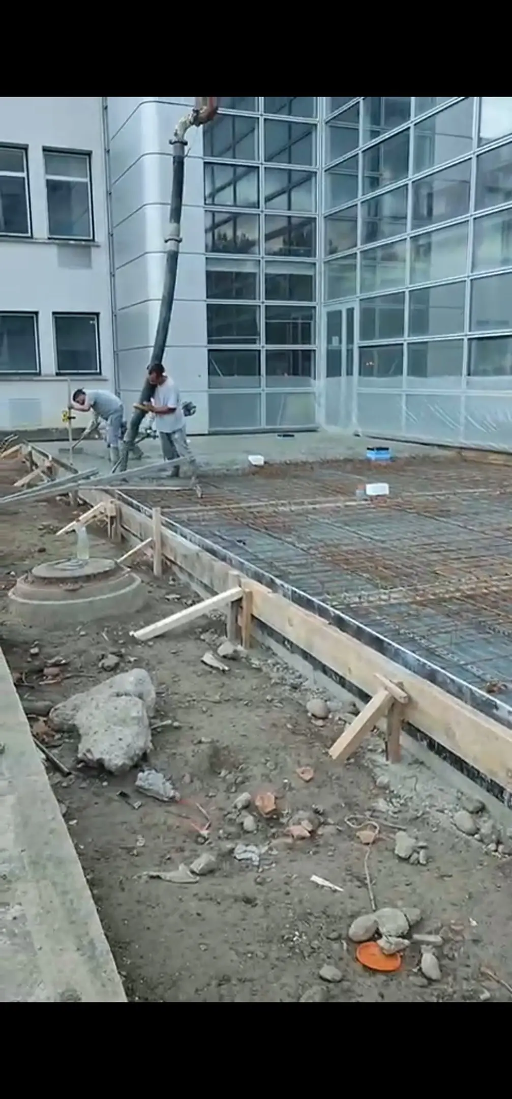 Ferraillage et coulage de dalle béton devant un bâtiment vitré