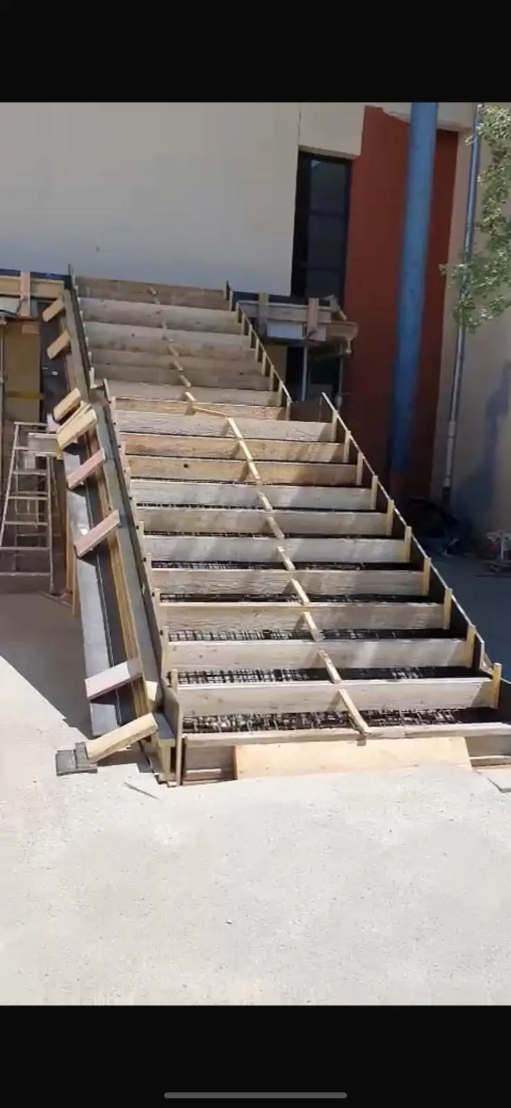 Coffrage et ferraillage d'un escalier en béton armé sur un chantier de maçonnerie