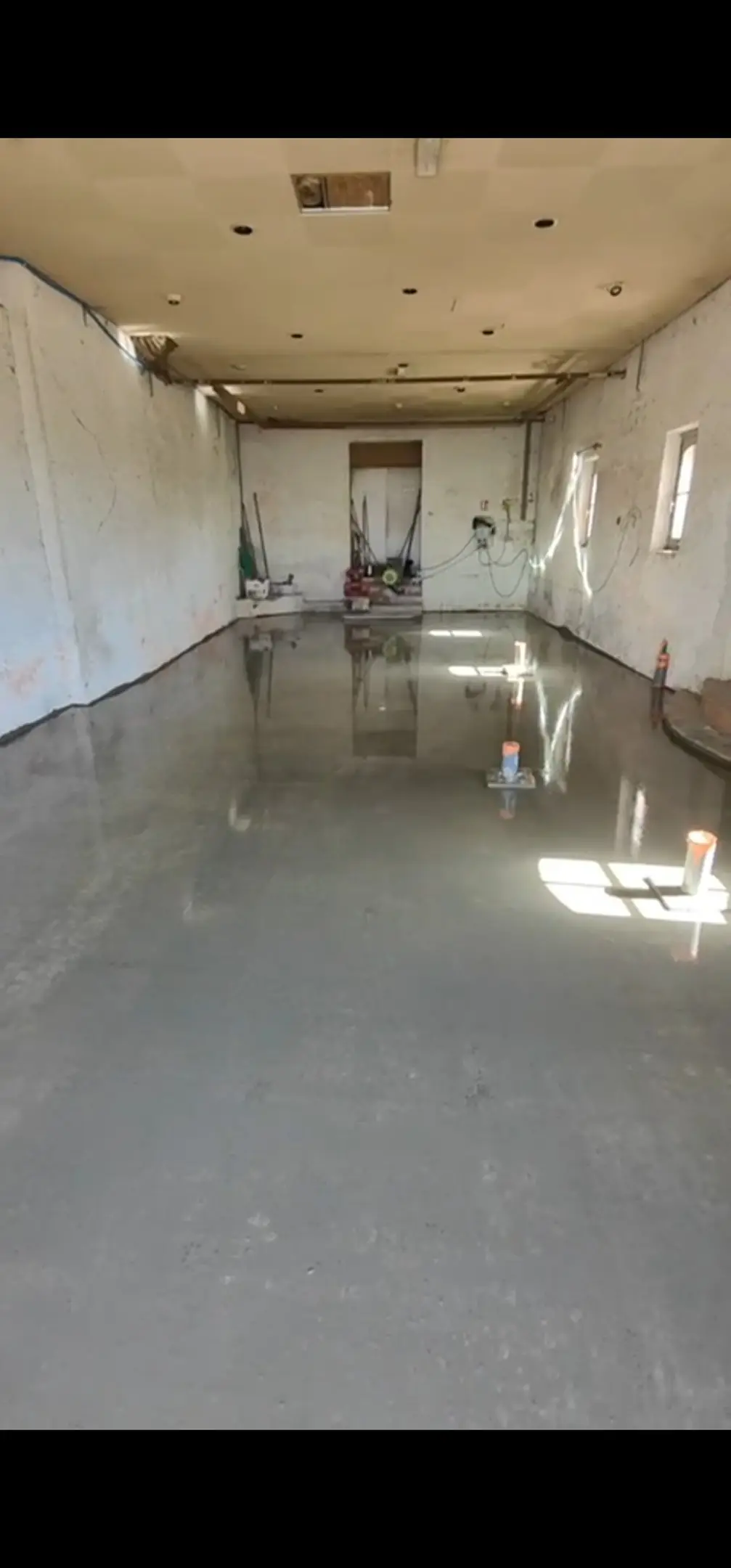 Sol intérieur en béton lissé après rénovation, pièce aux murs blancs
